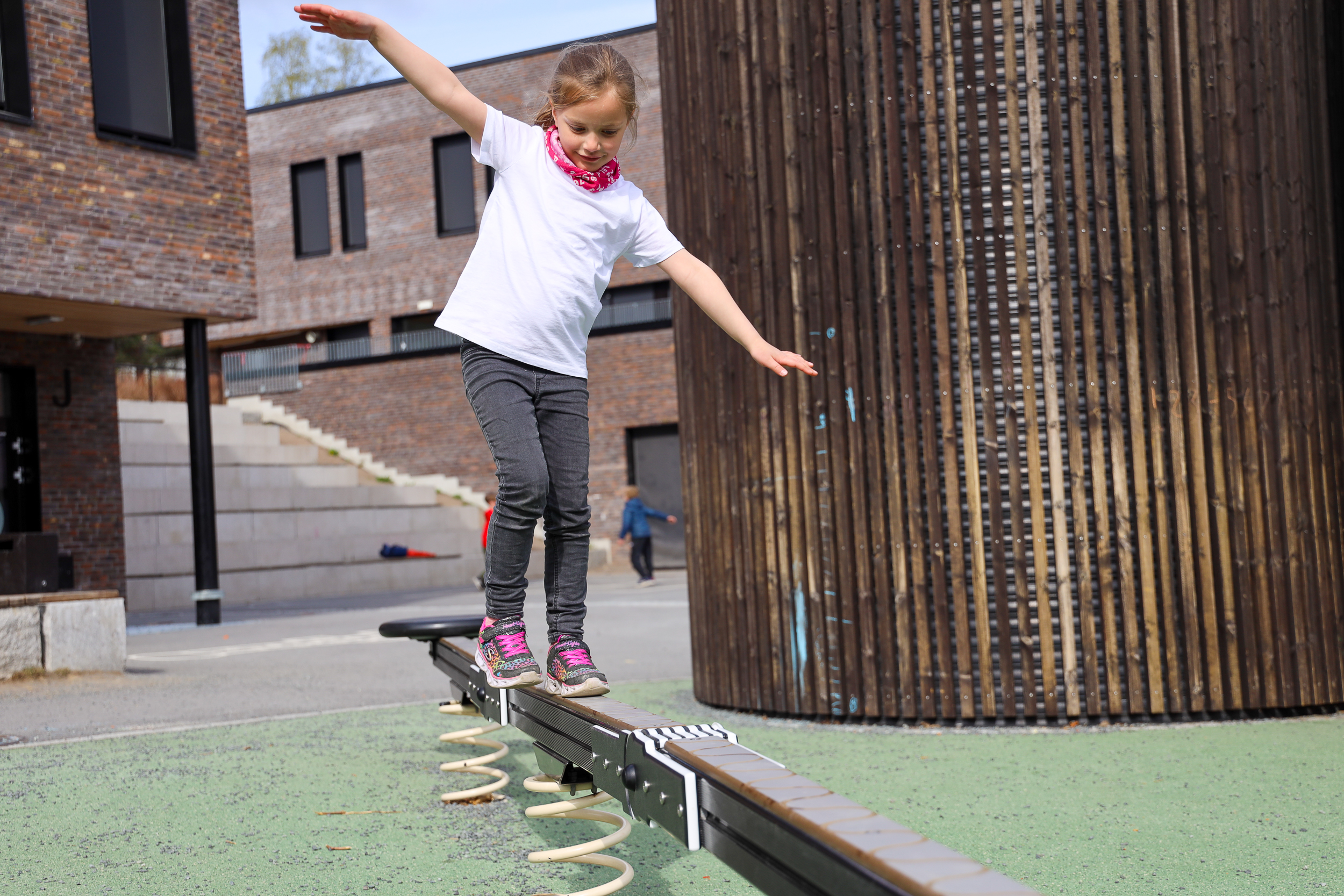 Jente balanserer i skolegården.