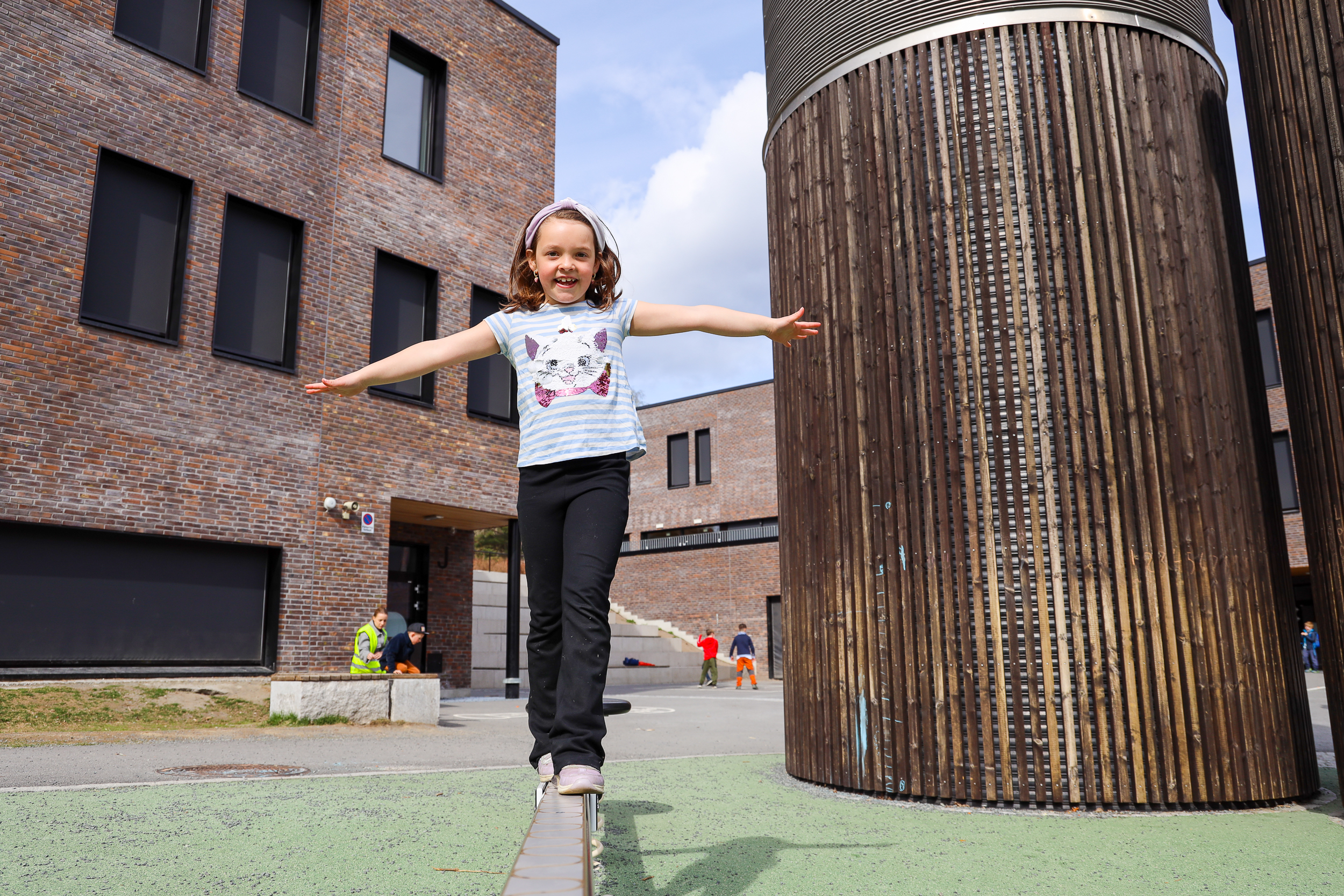 Jente balanserer i skolegården.